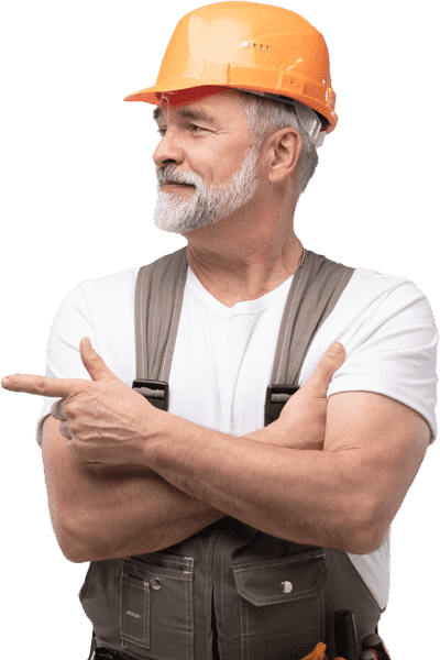 Senior male construction worker with a grey beard wearing an orange hard hat and grey overalls, pointing to the side against a white background.